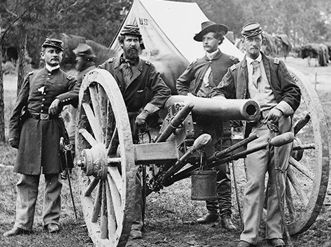 Picture of Sgt. John Kennedy with other men standing in front of a cannon