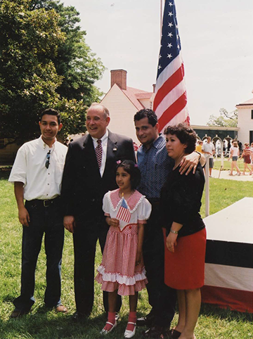 Photo of family standing by a flag with Director Aguirre at an outdoor ceremony
