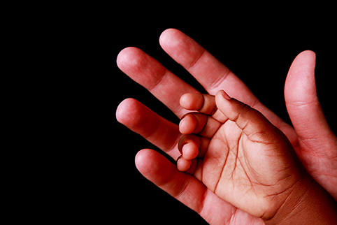 A child's hand resting on the palm of an adult hand