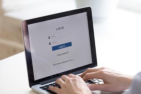 Photo of a laptop monitor with the USCIS online account sign on screen with a persons hands on the keyboard