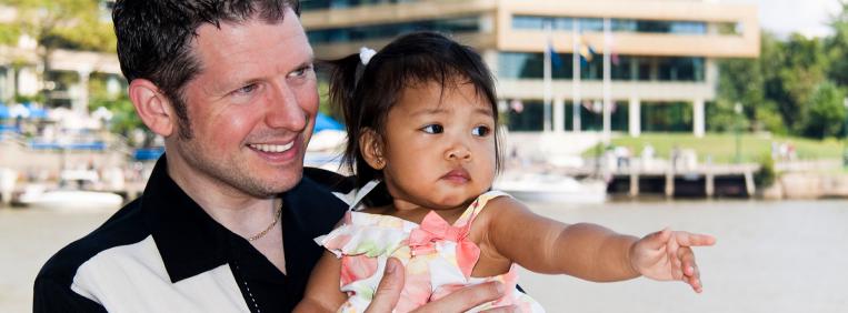 Man holding young girl and she is pointing into the distance.